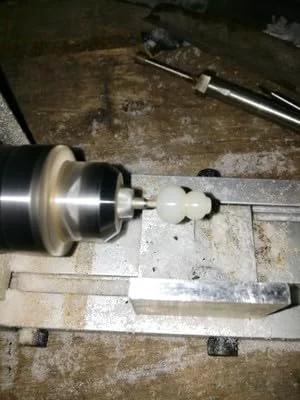 Mini wood lathe close-up turning a small light-colored workpiece between centers