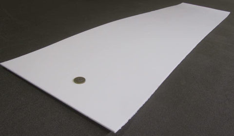 Virgin PTFE Sheet One Eighth Inch Thick, Twelve By Forty Eight Inches, on dark surface, with coin for scale, nonstick material