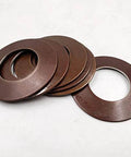 Front view of several brown metal disc springs (cup springs) stacked with central holes