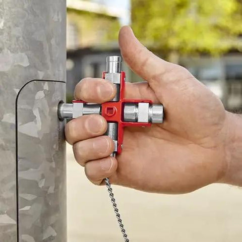 Hand using All-In-One Universal Control Cabinet Key With Nine Die-Cast Zinc Profiles for electrical cabinet access outdoors.