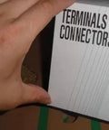 Front view of terminals and connectors packaging; hand holding a white cover labeled TERMINALS & CONNECTORS