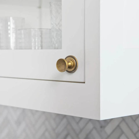 Antique Brass Cabinet Knobs With Gear Like Backplate Six Pack, Vintage Round Cup Design, installed on a white cabinet