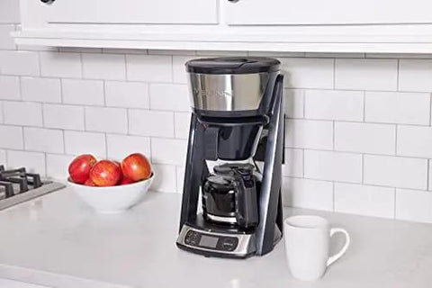 Heat N Brew 10 Cup Programmable Coffee Maker With Stainless Steel Finish on kitchen counter next to a cup and apples