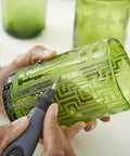 Rotary engraving tool with comfort grip engraving a green glass tumbler; close-up view