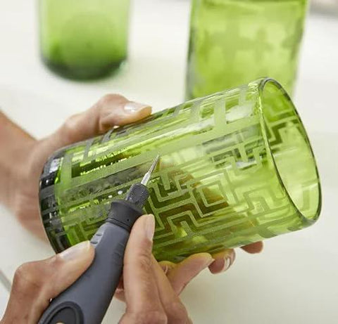 Rotary engraving tool with comfort grip engraving a green glass tumbler; close-up view