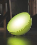 Go White And Color Portable Dimmable LED Smart Light Table Lamp emitting green glow, placed on dark surface, compatible with Alexa HomeKit.
