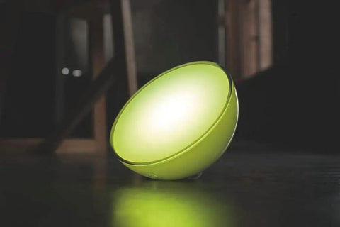 Go White And Color Portable Dimmable LED Smart Light Table Lamp emitting green glow, placed on dark surface, compatible with Alexa HomeKit.