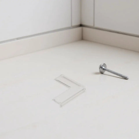 Transparent silicone corner protector next to a screw, part of Eight Pack Silicone Corner Protectors For Baby Proofing And Home Safety Edge Guards