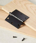 Interior Door Hinges Square 3.5 Inch Matte Black Pack Of 12 With 72 Mounting Screws Durable Steel Construction, shown on wood surface