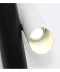 Close-up of Rock Solid Black Iron Wall Sconce With Pivot Led Fixture and Chill Warm Glow illuminating a circular white shade.
