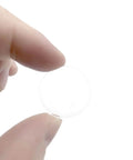 A hand holding a clear 1-inch round PVC spacer from the 25 Pack Clear Round Glass Table Protectors.