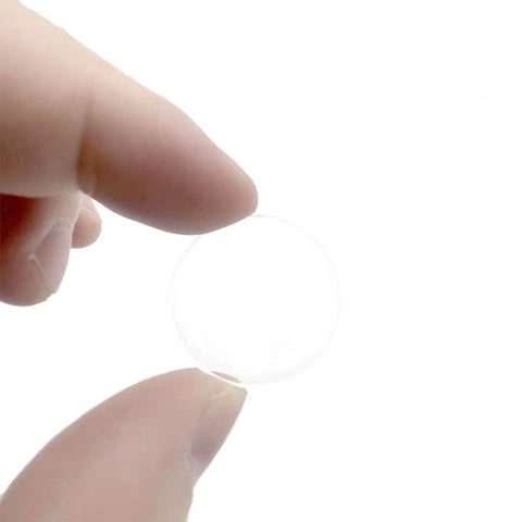 A hand holding a clear 1-inch round PVC spacer from the 25 Pack Clear Round Glass Table Protectors.
