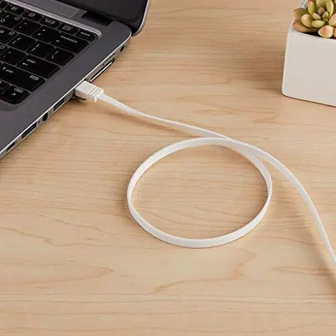 Flat Cat6 Ethernet Cable 100Ft Snagless Patch Cord With Gold Plated Connectors connected to a laptop on a wooden desk surface.