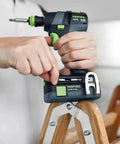 Hands using Built Tough 18V Compact Cordless Drill Workhorse Kit with keyless chuck on a wooden ladder.