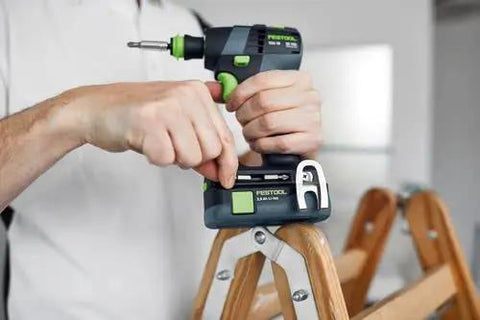 Hands using Built Tough 18V Compact Cordless Drill Workhorse Kit with keyless chuck on a wooden ladder.