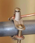 Heavy Duty Bronze Water Pipe Ground Clamp Fits One Quarter To Two Inches attached to metal pipe with copper wire.