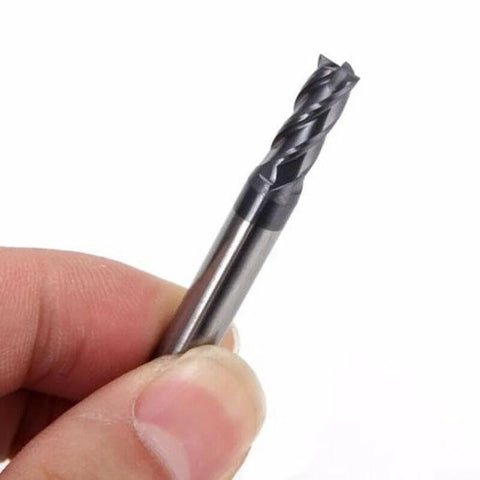 Close-up of AlTiN-coated solid carbide end mill, 4-flute, held between fingers for scale.
