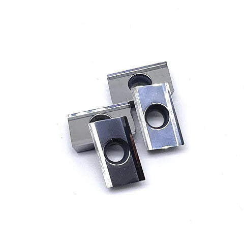 Two APKT-style milling inserts with central mounting holes, silver and black metal blocks.