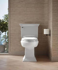 White elongated toilet, front view, installed in a modern bathroom with wood-paneled walls.