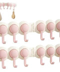 Heavy Duty Six Hook Adhesive Wall Rack With Smooth 180 Degree Swivel And Easy No Drill Mount Ideal For Stashing Towels Keys Utensils And Everyday Gear Inside Or Out with pink hooks on a white background.