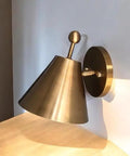 Handcrafted Brass Wall Sconce with Finial Vintage Hardwired Light showcasing conical shade and ball finial against wall.