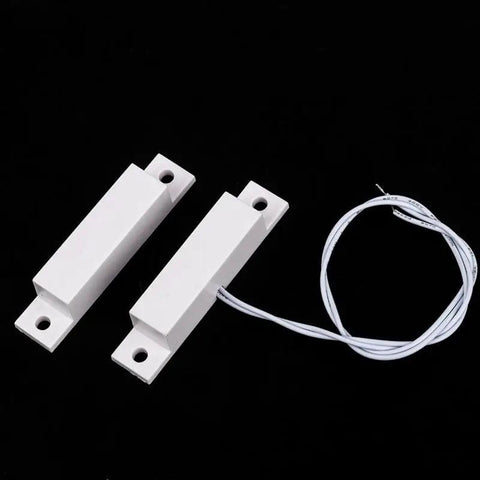 MC-32 NC Surface Mount Magnetic Reed Switch for Home Security, white finish, two components and wire against black background