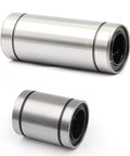 Two stainless steel linear motion bearings in different sizes; cylindrical metal housings with black inner races