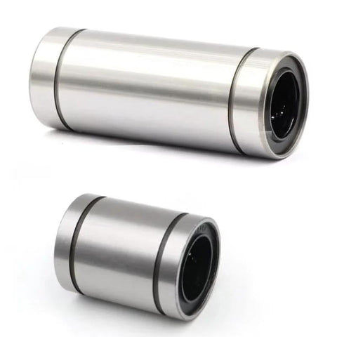 Two stainless steel linear motion bearings in different sizes; cylindrical metal housings with black inner races