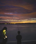 Man using Blue Han Compact Keychain LED Flashlight with Twist Head at dusk by a lake, highlighting IPX7 Water Resistant feature