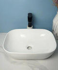 USZWBY Vessel Sinks Square Rounded Corner Simple Sink Ceramic Above Counter Wash Basin displayed on marble countertop with faucet.