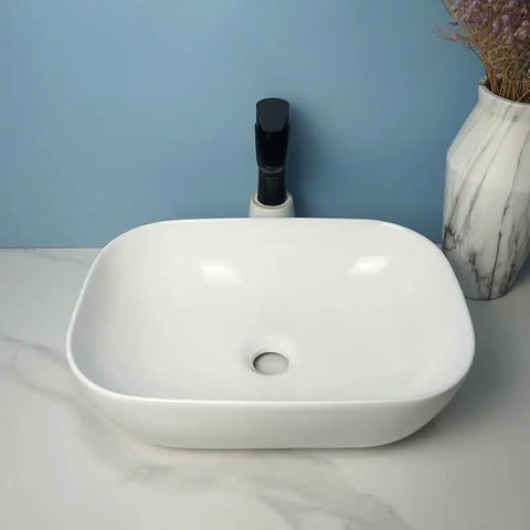 USZWBY Vessel Sinks Square Rounded Corner Simple Sink Ceramic Above Counter Wash Basin displayed on marble countertop with faucet.