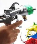Pro Grade Double Nozzle Spray Gun Featuring 1.3MM Steel Tip And 40CM Wide Pattern For Slick Finishes Pressure Feed Pneumatic Paint Sprayer Rock Solid held in hand with colorful paint splashes.