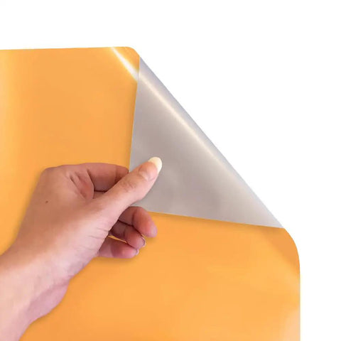 Hand peeling back the top layer of Electric Yellow EasyWeed HTV Heat Transfer Vinyl 11.8 by 3ft Roll for Crafts.