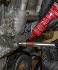 LOCTITE 263 red automotive threadlocker being applied to a bolt on an engine, close-up with gloved hands.