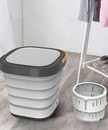 Total Game Changer Portable Mini Washing Machine With Foldaway Compact Build For Grabbing Laundry On The Fly lightweight gray washing machine beside a collapsible basin on wooden floor