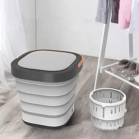 Total Game Changer Portable Mini Washing Machine With Foldaway Compact Build For Grabbing Laundry On The Fly lightweight gray washing machine beside a collapsible basin on wooden floor