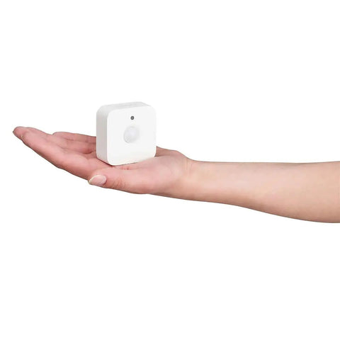 Hand holding a white Indoor Smart Motion Sensor 2 Pack With Daylight Sensing Auto On When You Roll In And Auto Off When You Roll Out