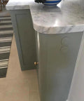 Close-up of a light gray cabinet with a marble countertop featuring a tamper resistant electrical outlet for convenient use.