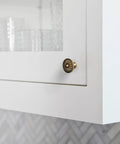 Close-up of Vintage Antique Brass Sunburst Cabinet Knob on white kitchen cabinet, showing distressed floral design.