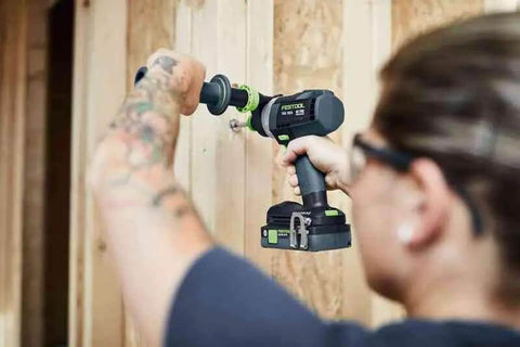 Person using Badass Cordless Drill Driver Featuring Ec Tec Brushless Motor on wooden wall for drilling tasks.