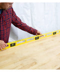Person using a durable 48 inch polystyrene level with 0.001 inch accuracy, built in the USA, on a wooden surface for leveling.