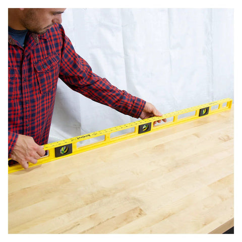 Person using a durable 48 inch polystyrene level with 0.001 inch accuracy, built in the USA, on a wooden surface for leveling.