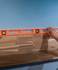 Non-conductive Structo-Cast 48 Inch I-Beam Level With Three Replaceable Acrylic Vials Delivers Precise 360-Degree Readings From Any Angle shown in use on wood paneling