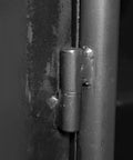 Close-up of black 5-inch heavy-duty weld-on barrel hinge for metal gate, showing greaseable zerk and ball bearings installed on surface.