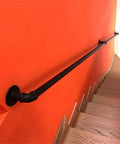 Industrial Water Pipe Stair Handrail Heavy Duty Wrought Iron Banister With Locking Brackets Straightforward Wall Mount for Lofts Attics on orange wall