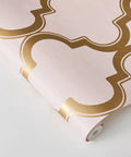 Pink and Metallic Gold Marrakesh Peel and Stick Wallpaper with Moroccan Trellis Design on Matte Backdrop, roll view.