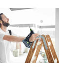 Rugged 18V Cordless Drill With Keyless Chuck And Belt Clip Compact Ergonomic Handle used by man on ladder for fastening tasks.
