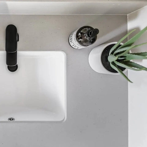 Top view of Undermount White Bathroom Sink 16 By 11 Narrow Rectangular Vanity Sink With Overflow Vitreous China Ceramic Fits 18 Inch Vanity Opening 16 By 11 Modern Durable Bath Fixture Easy Install with faucet, plant, and soap dispenser.