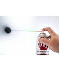 Hand using Dry Graphite Film Spray Anticorrosive Lubricant with Quick Dry Formula on white metal surface, black matte finish visible