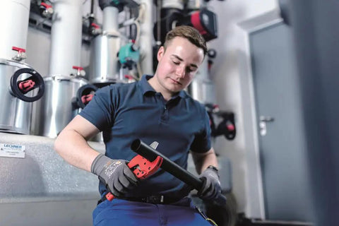 Man using Pro Grade Plastic Pipe Cutter with stainless steel blade and rubberized handle in workshop setting.